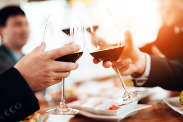 Close up. Meeting with chinese businessmen in restaurant. Men are toasting with wine glasses.
