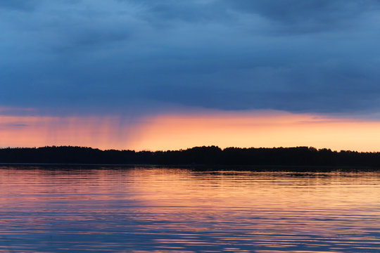 Sunset on the Vuoksa lake. It is small rain on the horizon. © makarova