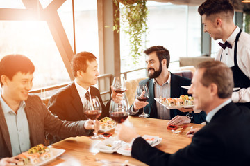 Meeting with chinese businessmen in restaurant. Waiter brings sushi.