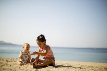 Cute little sisters sitting on a beach