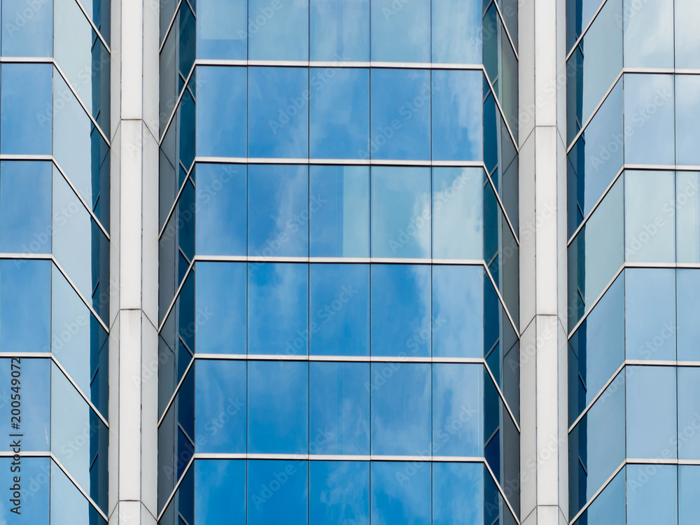 Poster Looking up to the office building and steel window system with reflection of cloud and sky on the glass,Business concept of future architecture.
