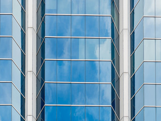 Looking up to the office building and steel window system with reflection of cloud and sky on the glass,Business concept of future architecture.