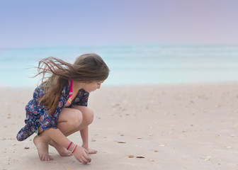 Young girl with long brown hair standing on the beach