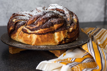 Twisted yeast pie with cinnamon and cocoa filling decorated with powdered sugar