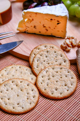 Still life Roquefort cheese, red and green grapes, crackers on wooden plate