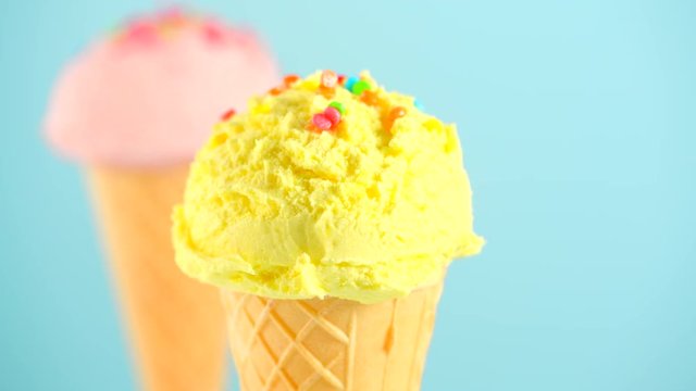 Ice cream. Various icecream scoops in waffle cones rotated on blue background. Strawberry or raspberry, banana or lemon flavors. Sweet dessert closeup. 4K UHD video footage. 3840X2160