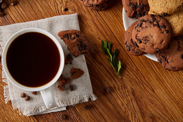 Coffee cup, jar with coffee beans, cookies over rustic background, selective focus, close-up, top view