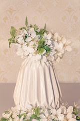 romantic floral composition with white flowers close-up, spring blossom bouquet in a beige vase on vintage background, with pattern and pastel colors. romantic, retro style with warm, soft colors 