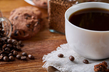 Coffee cup, jar with coffee beans, cookies over rustic background, selective focus, close-up, top view