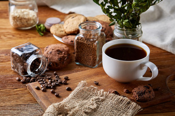Coffee cup, jar with coffee beans, cookies over rustic background, selective focus, close-up, top view