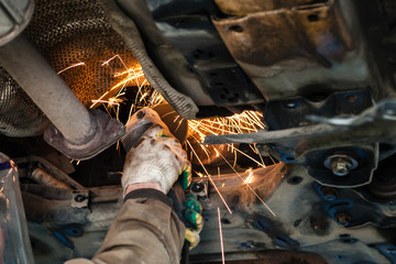 mechanic cleans muffler pipe by angle grinder