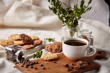 Coffee cup, jar with coffee beans, cookies over rustic background, selective focus, close-up, top view