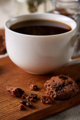 Coffee cup, jar with coffee beans, cookies over rustic background, selective focus, close-up, top view