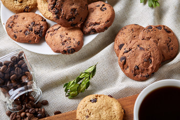 Coffee cup, jar with coffee beans, cookies over rustic background, selective focus, close-up, top view