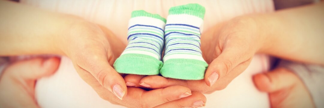 Pregnant Woman Holding Baby Shoes