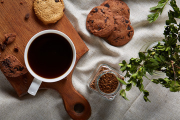 Coffee cup, jar with coffee beans, cookies over rustic background, selective focus, close-up, top view