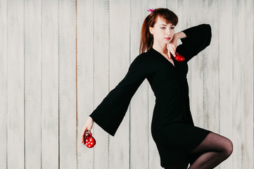 a young dancing girl in black dress, with castanets, light background
