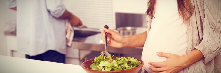 Pregnant woman mixing a salad in the kitchen