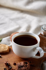 Coffee cup, jar with coffee beans, cookies over rustic background, selective focus, close-up, top view