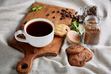 Coffee cup, jar with coffee beans, cookies over rustic background, selective focus, close-up, top view