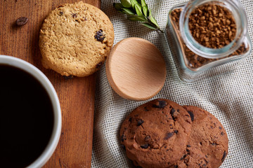 Coffee cup, jar with coffee beans, cookies over rustic background, selective focus, close-up, top view