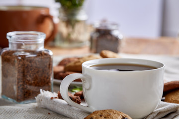 Morning coffee in white cup, chocolate chips cookies on cutting board close-up, selective focus