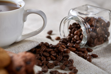Morning coffee in white cup, chocolate chips cookies on cutting board close-up, selective focus