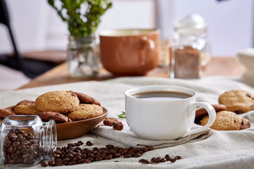 Morning coffee in white cup, chocolate chips cookies on cutting board close-up, selective focus