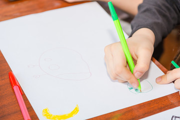The child is drawing. Draws on a piece of paper. Children have fun. Draws a postcard. The child draws with a pencil.