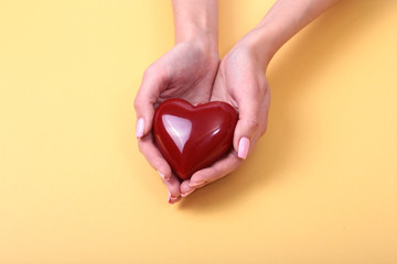 A woman holds a red heart in her hands