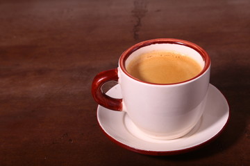 A cup of espresso coffee on a dark wooden background