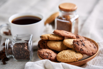 Side view of a plate of chocolate chip cookies on a white plate on homespun tablecloth, selective focus