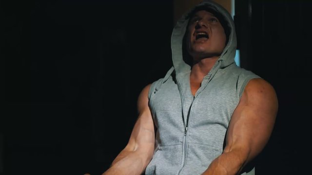 Brutal man shakes his biceps in the gym