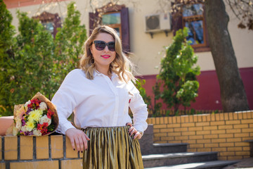 Fototapeta premium A woman of plus size, American or European appearance walks in the city enjoying life. A young lady with excess weight, stylishly dressed in jacket at the center of the city. Natural beauty 