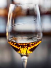 Close-up macro detail of multiple bottles of liquor reflected in a whisky filled wine glass, gray bartop. Shallow depth of field, vertical orientation. Kyoto, Japan. Alcohol and addiction concept.