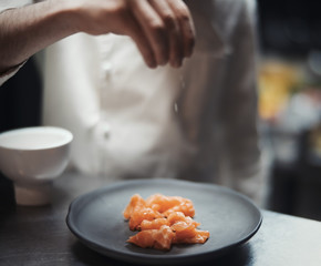 Restaurant Chef cook preparing salmon filet and salting it.