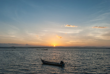 sunrise on the beach with wooden boat on the sea.