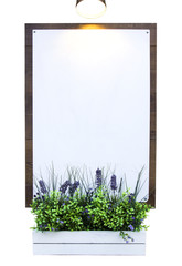 Blank billboard poster on wooden wall with flowers in white pot and lamp that illuminates empty white board, isolated, for restaurant cafe food menu design, advertisements
