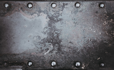 Metallic background painted with multicolored paint with large old rivets