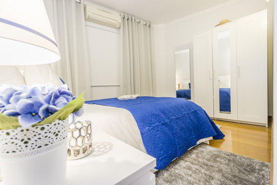 An elegant bedroom arranged in white and blue with turn on lights on bed shelves