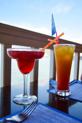 Two exotic cocktails on table, sea background