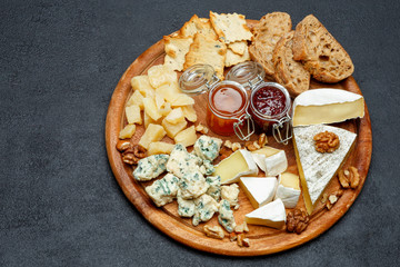 Brie cheese on a wooden Board with bread and sweet jam