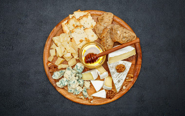 Brie cheese on a wooden Board with bread and sweet honey