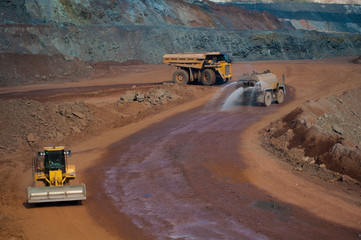 Heavy truck pours the road with water in the iron ore quarry. Dust removal, protection of the...