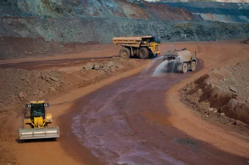 Fotobehang Vrachtwagen Heavy truck pours the road with water in the iron ore quarry. Dust removal, protection of the environment. Irrigation of the road from dust  © Yevhen