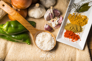 Still life with the ingredients to make a rice stew with vegetables and spices.