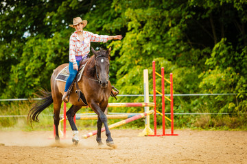 Cowgirl doing horse riding on countryside meadow