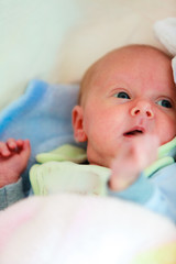 Little newborn baby lying in bed in pyjamas