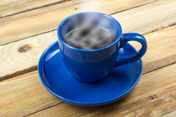 Blue cup of coffee on a wooden background.