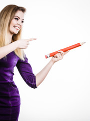 Smiling woman holds big pencil in hand